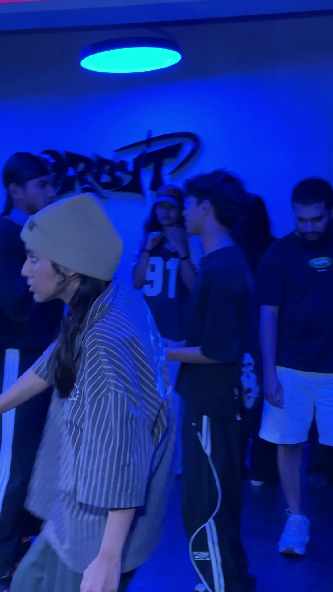 A dancer in a beanie mid-move in front of the ORBYT logo wall